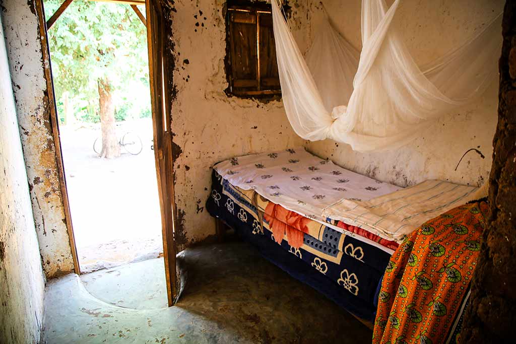 A small room with a bed in the corner, covered by a mosquito net.