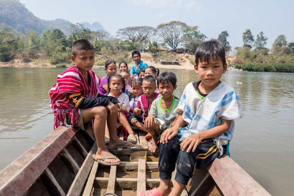 Multiple children are pictured in a boat along the Moei River.