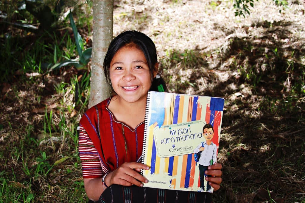 A girl in Guatemala proudly displays her “My Plan for Tomorrow” workbook.