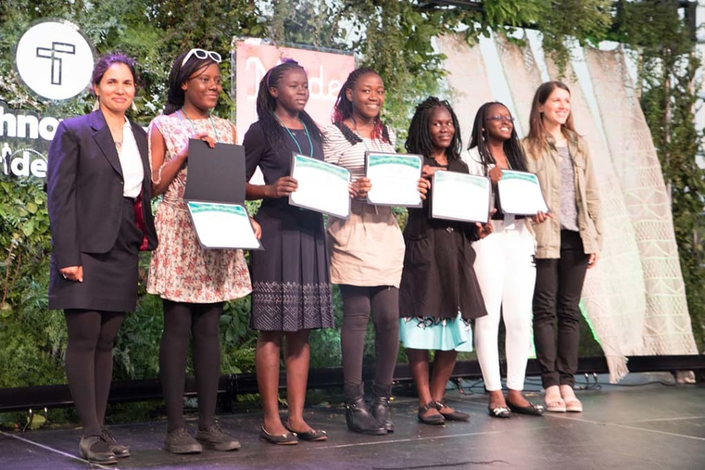 Five girls stand on stage receiving a technovation award from the presenters.