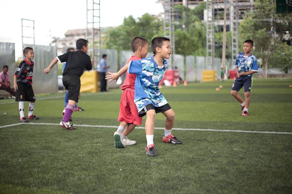 Two boys in soccer uniforms compete to receive a pass.