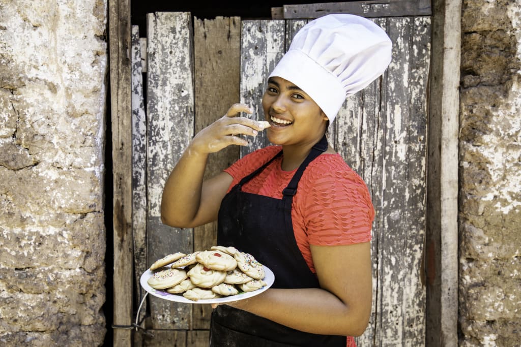 teen in a chef hat takes a bite of her freshly baked cookies