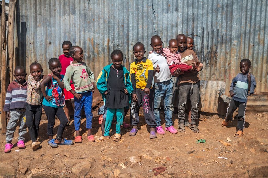 Children in Kenya standing in front of a metal wall.