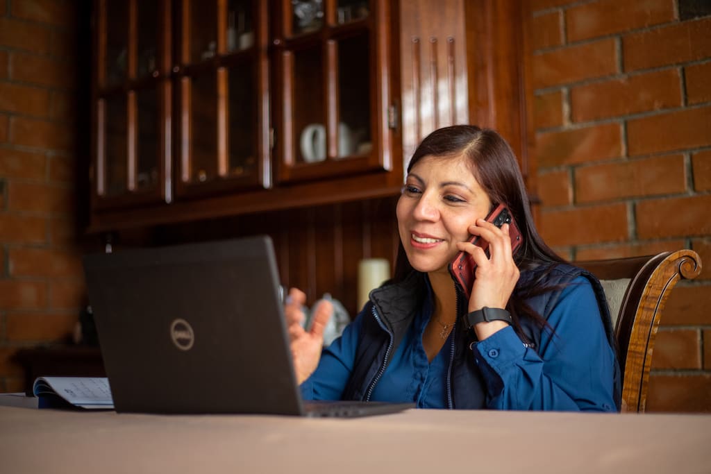 Partnership Facilitator Virgina sits at a desk speaking on a cell phone.