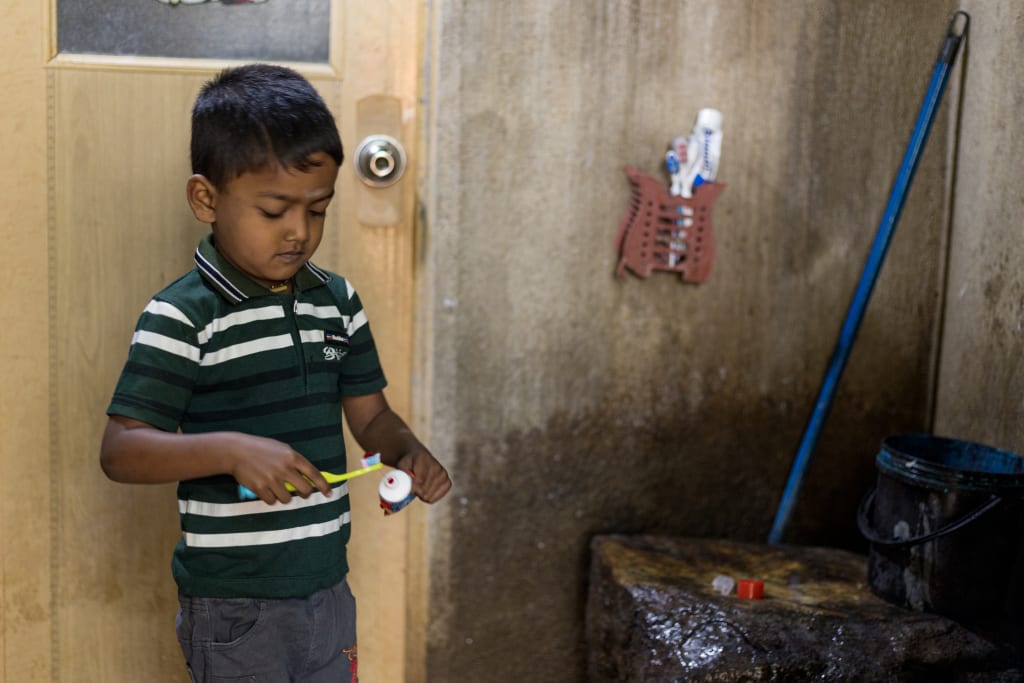 Rakshan stands in his bathroom at home while putting toothpaste on a toothbrush.
