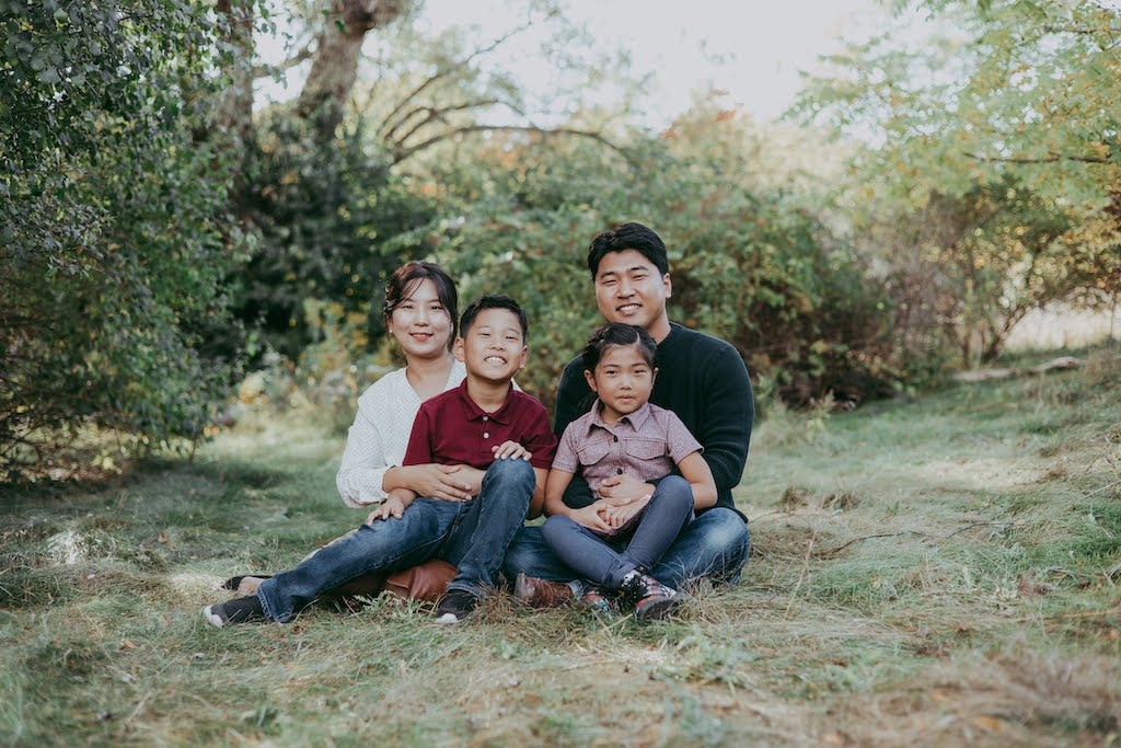 Compassion Ambassador John Park with his wife and two kids in a grassy field.