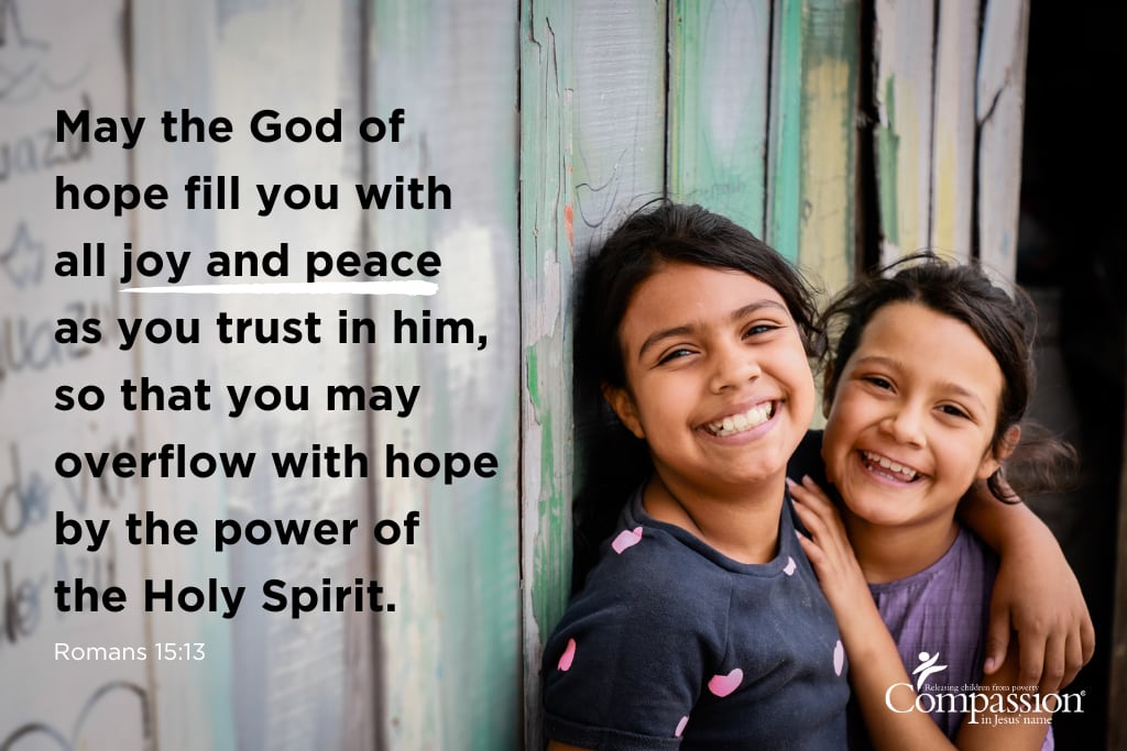 A Bible verse graphic that includes an image of two girls in Latin America and the text of Romans 15:13