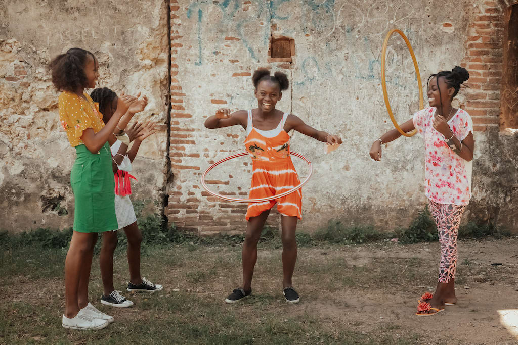 Girls laughing and playing with a hula hoop.