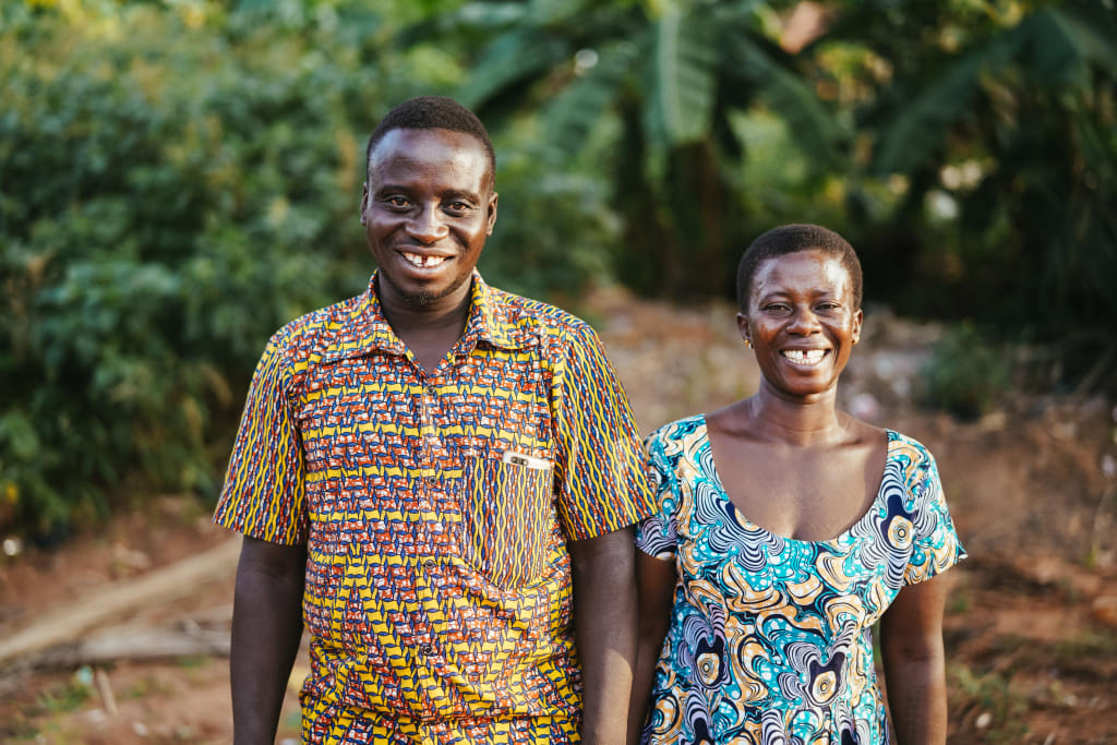 A man and woman stand side by side in patterned tops and smile.