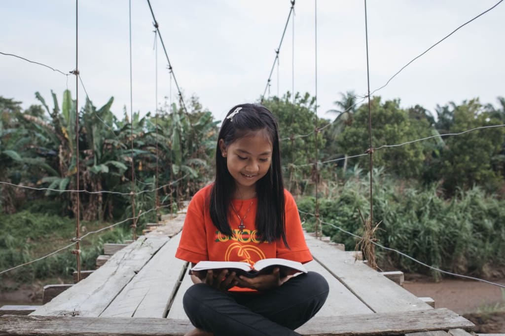 A girl in an orange shirt reads a book