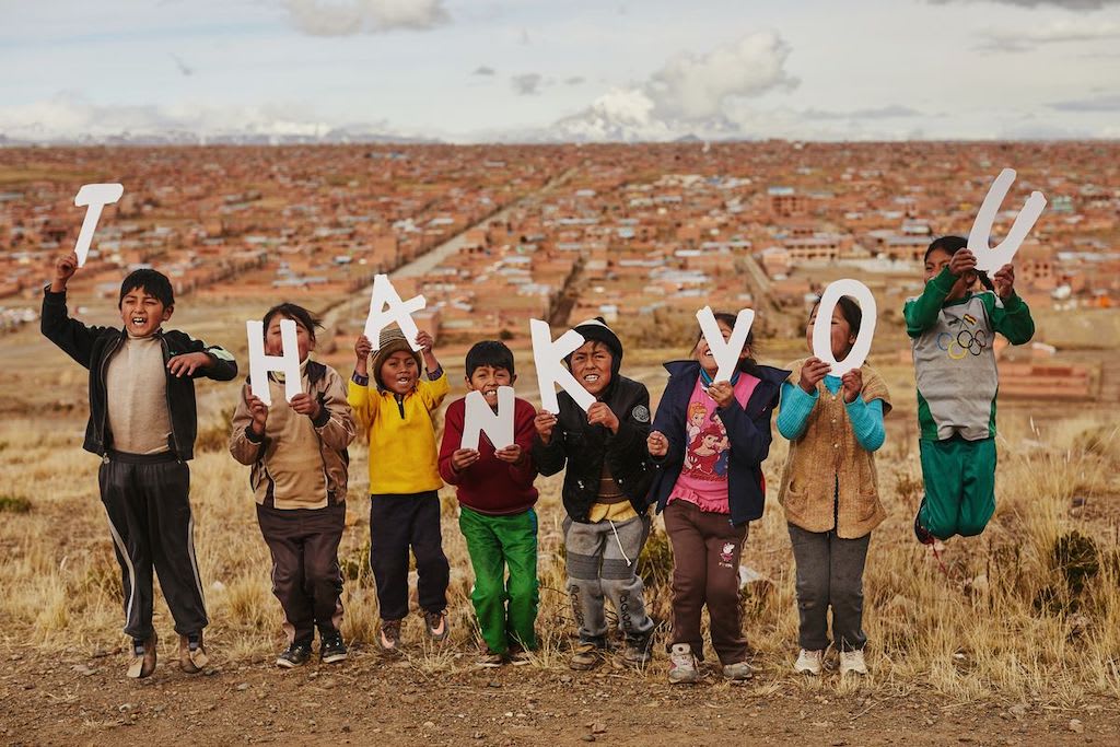 Children holding cutout letters that say 'thank you'.