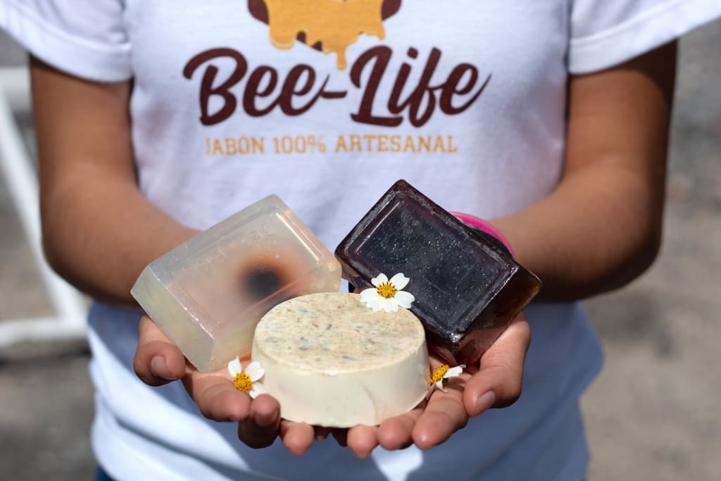 A girl holding a handful of honey soap bars.