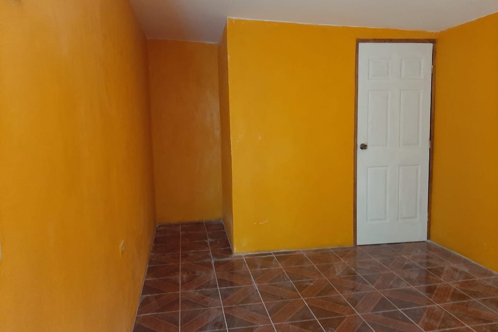 The interior of Francis' new bedroom. The walls are bright yellow and the floors are brown tile.