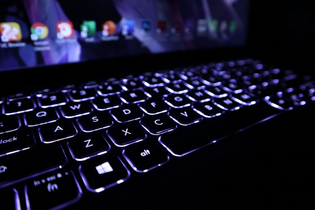 A laptop keyboard that is backlit in the dark.