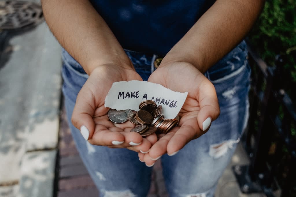 Hands holding coins and a note that says "Make a change".
