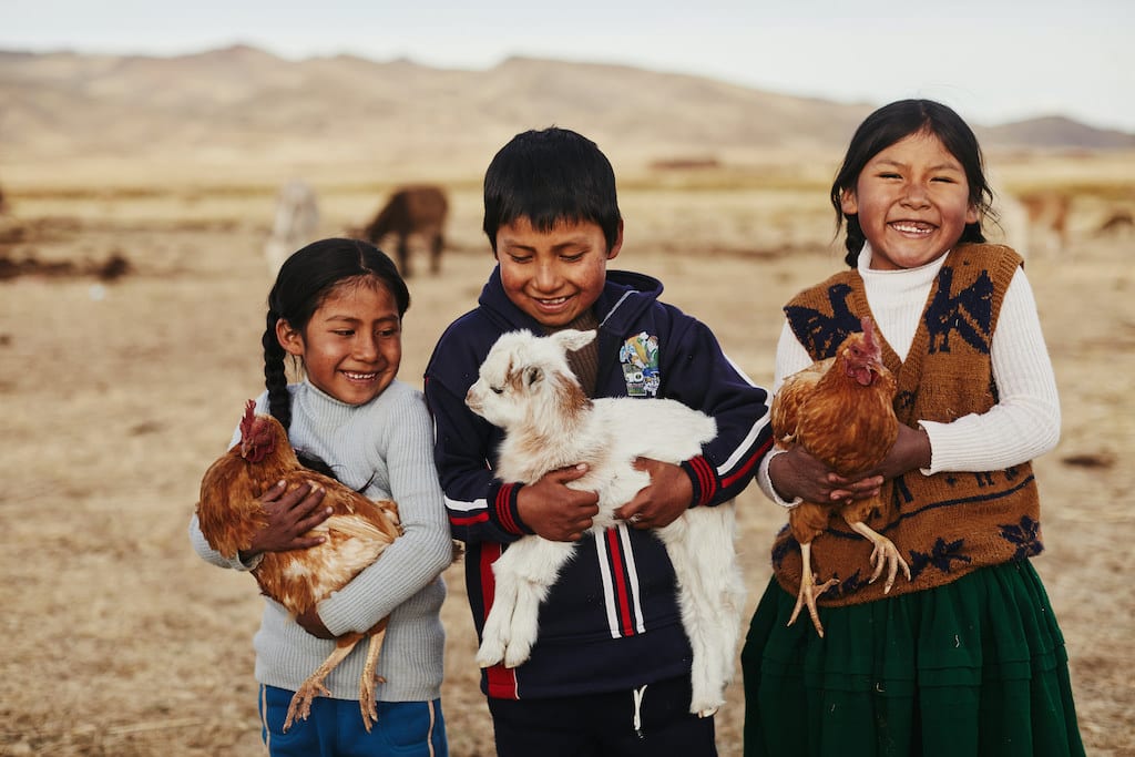 Three children carrying chicken and a goat in Bolivia