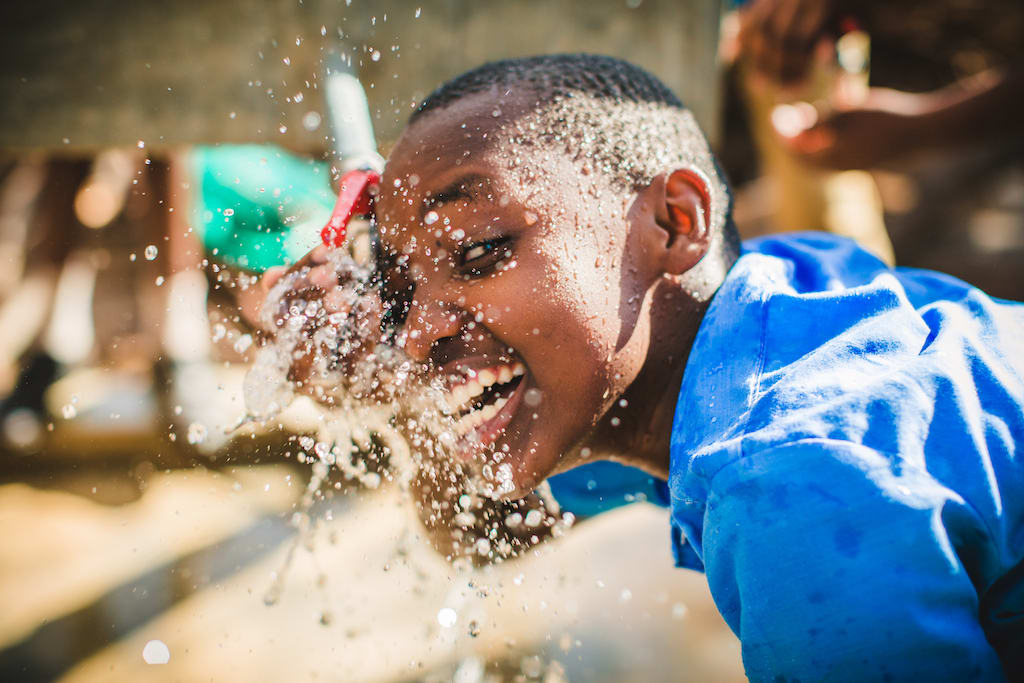 A boy drinking from an outdoor tap in Tanzania
