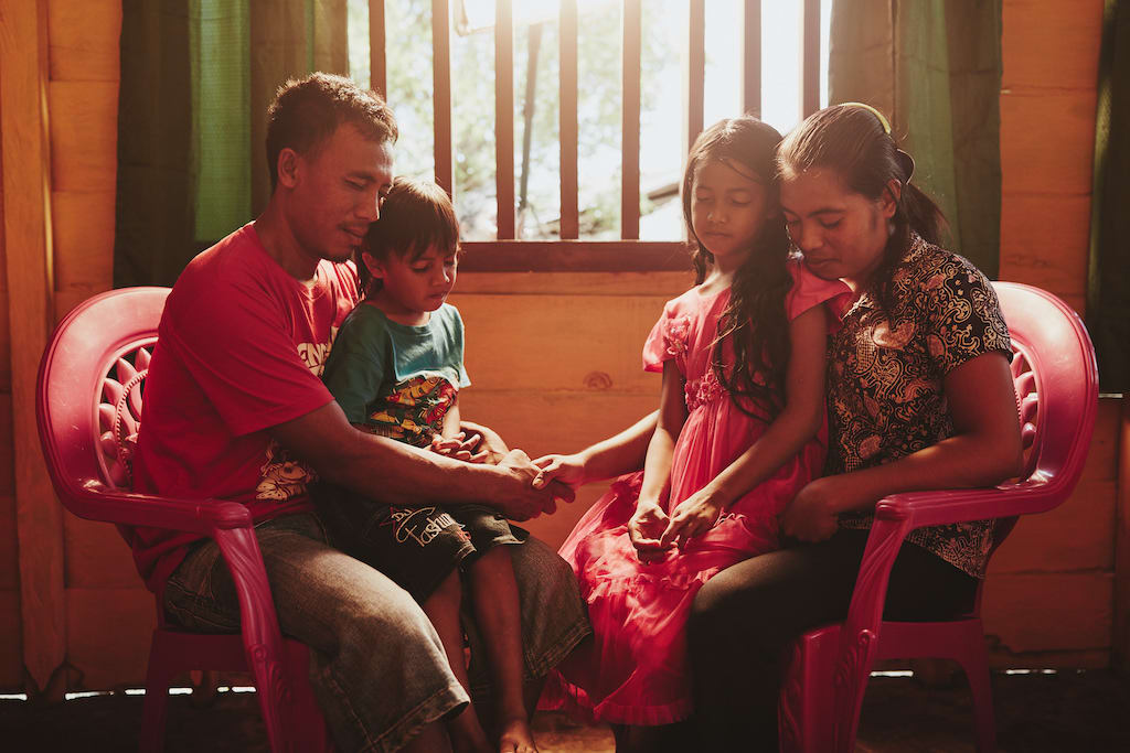 A family praying together in their home.