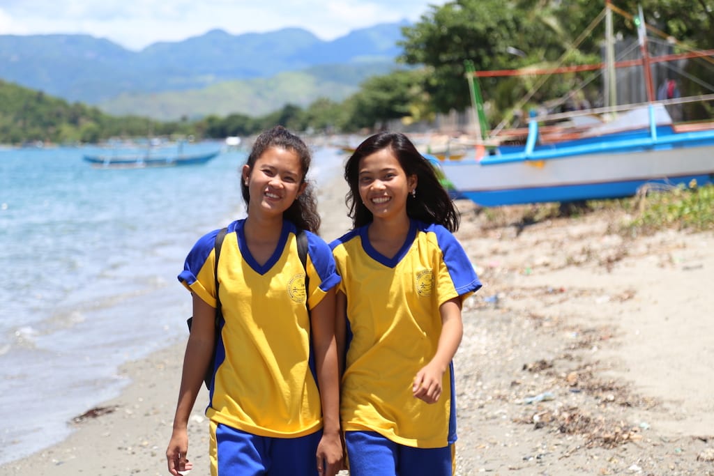 Two teen girls walking on a beach.