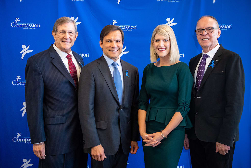 Dr. Wess Stafford, Santiago "Jimmy" Mellado, Allison Alley and Barry Slauenwhite pose in front of a blue Compassion backdrop.
