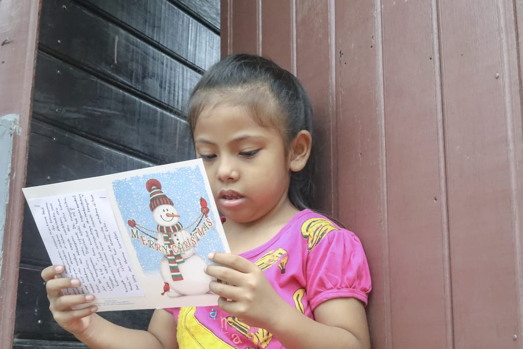 A girl reads a Christmas card from her sponsor.