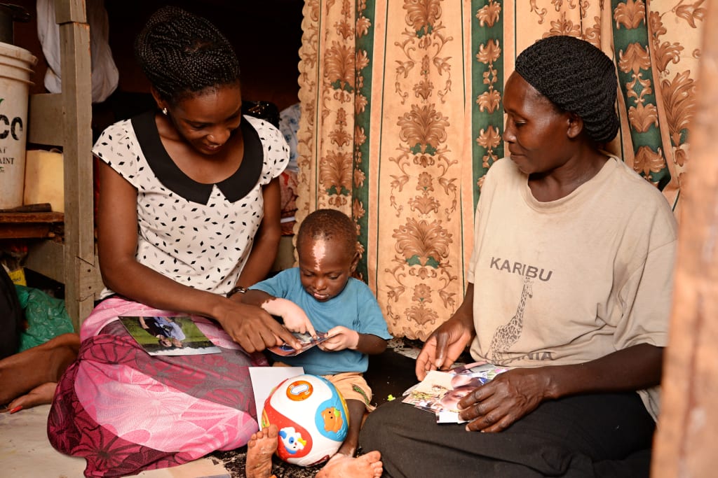 Shakul is at his home with Namatovu opening a gift. He has a soccer ball toy infront of him.