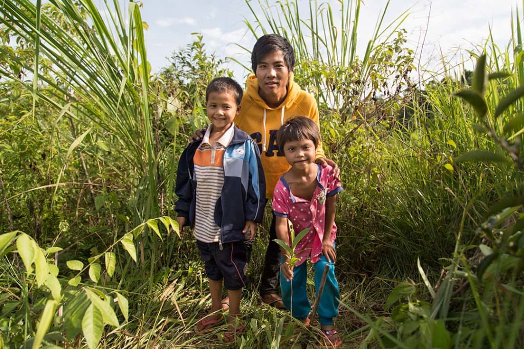 A dad stands in a field with his two children, a girl and a boy.