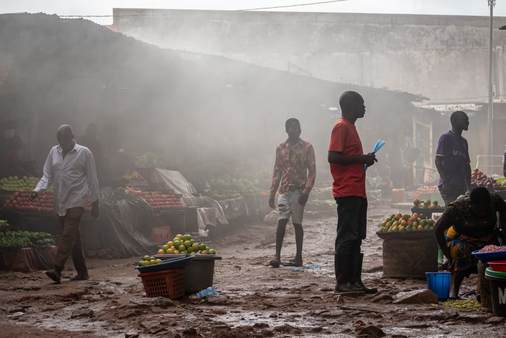 Four men stand in a smokey marketplace.