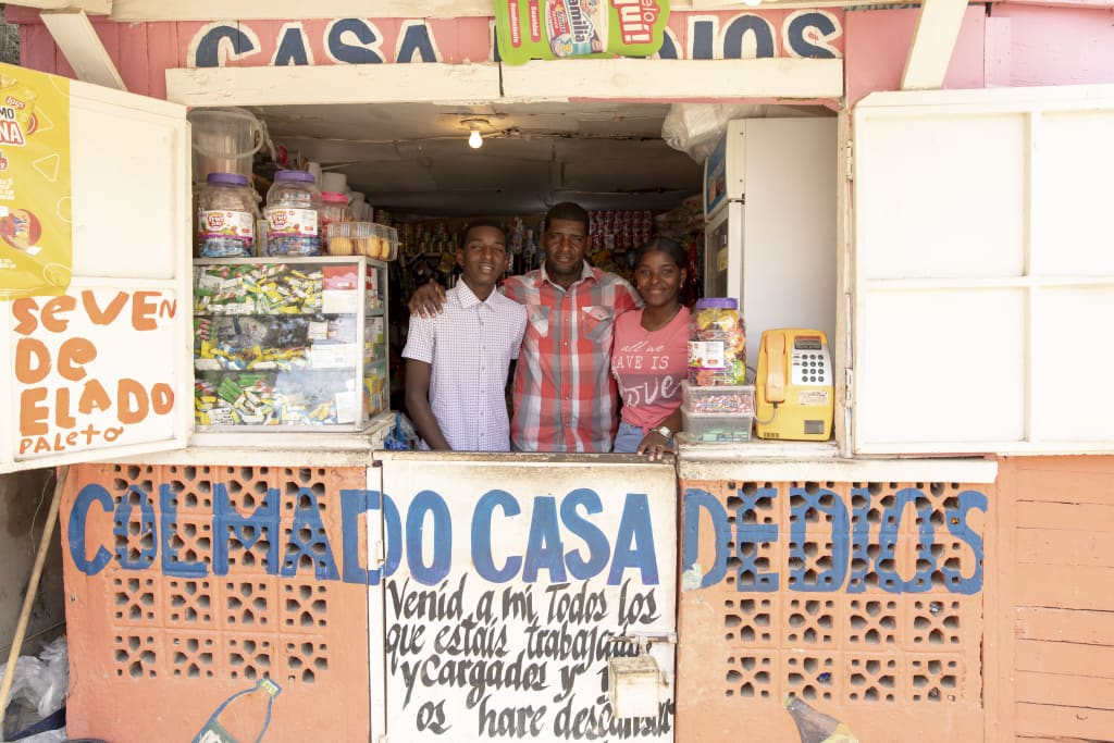 Daniel, Jose and Daniela are standing inside the little grocery store named “House of God” that Jose opened after dropping drugs and alcohol.