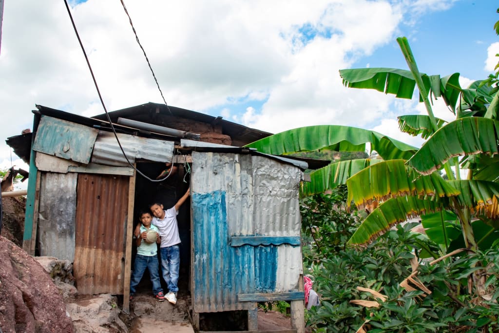 Two boys standing in the doorway of their small home.