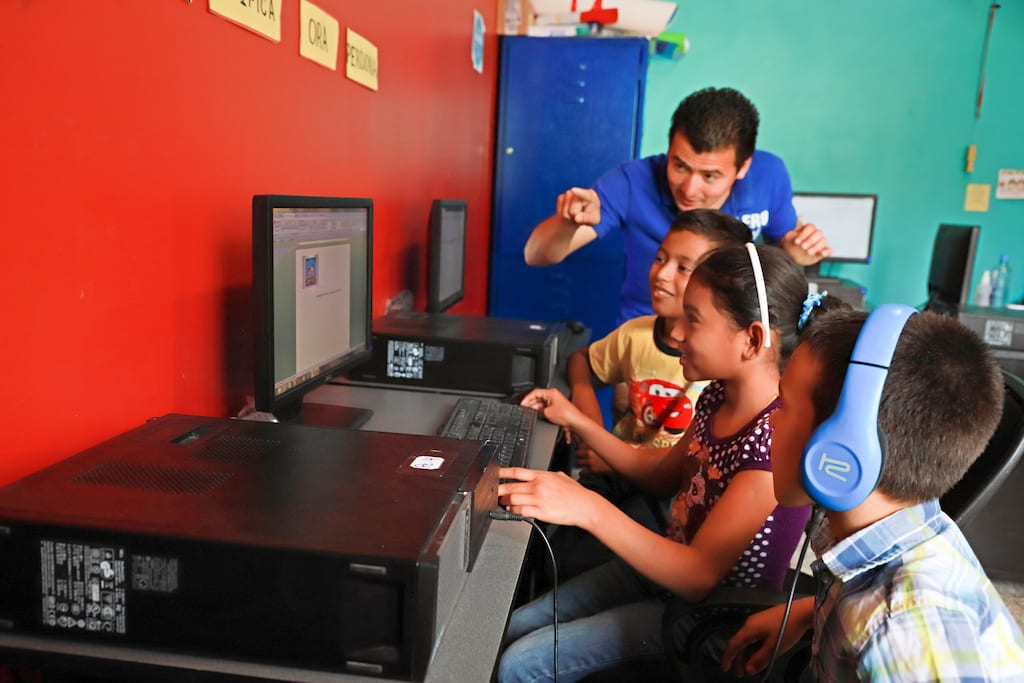 A group of students and their teacher working in a computer lab.