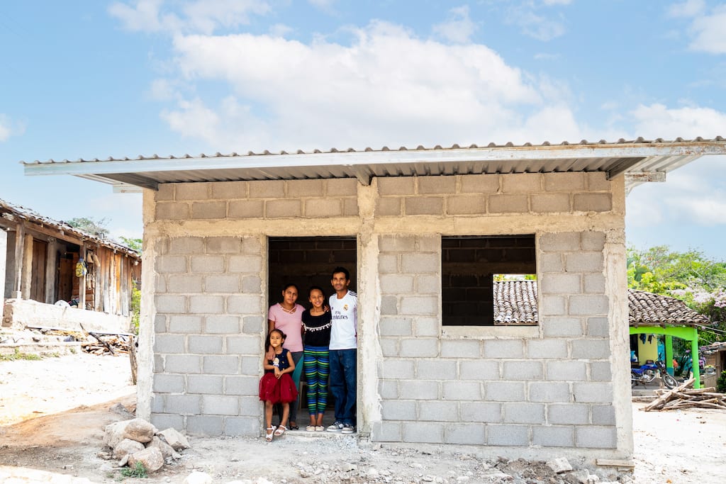 A family standing in the doorway of their new house.