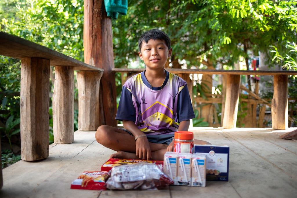 A Thai boy sits with a food package delivered by his Compassion centre. Food packs are one of the gifts in the Gifts of Compassion gift guide.