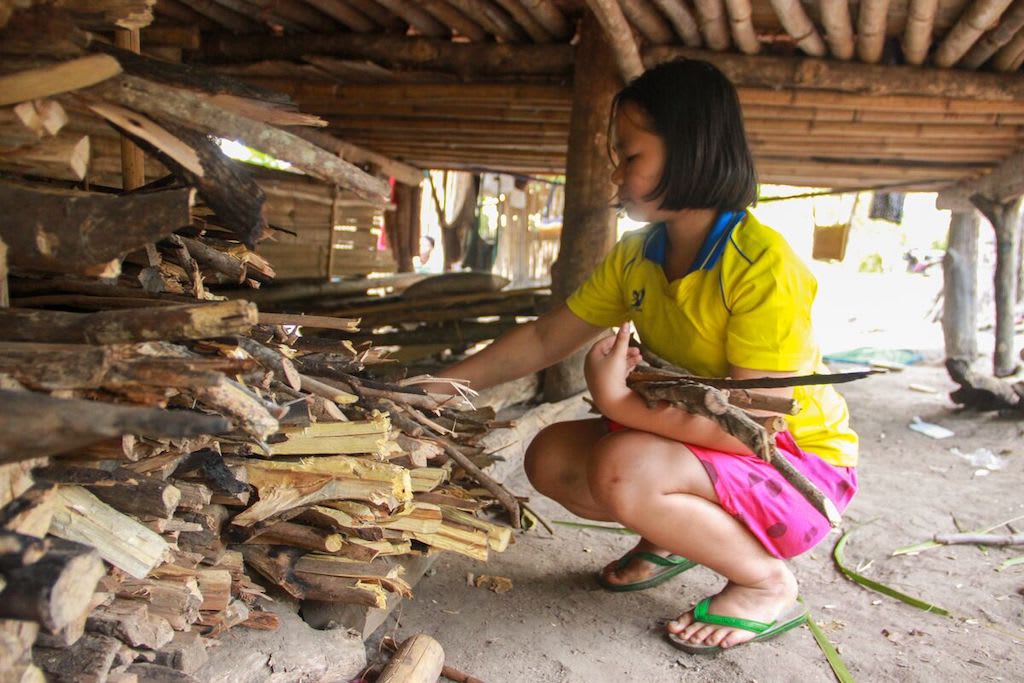 A Thai girl stacking wood.