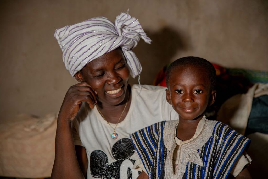 Achille and his mother, Seraphine. Seraphine is looking at Achille and smiling, while Achille grins at the camera.