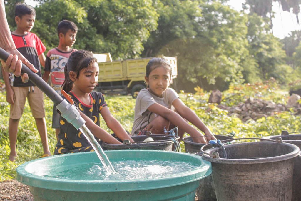 Yunita and other children collect water from the new well in their community.