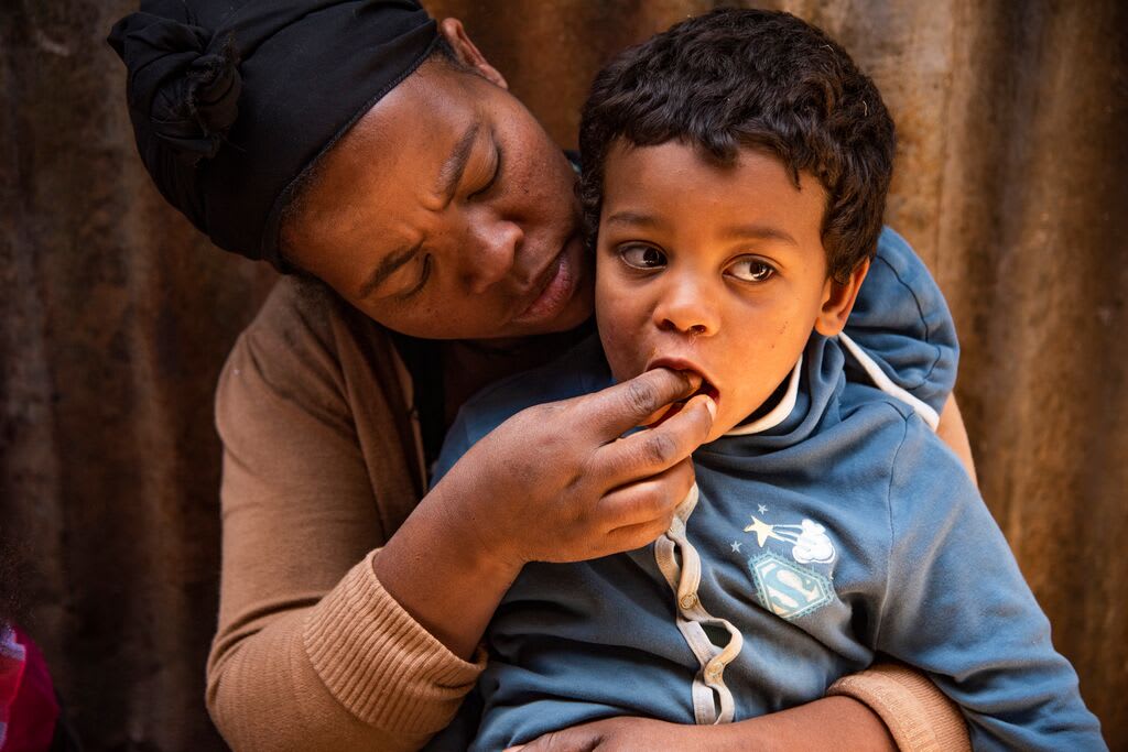 Abiyot feeds her young son some bread into. his mouth.