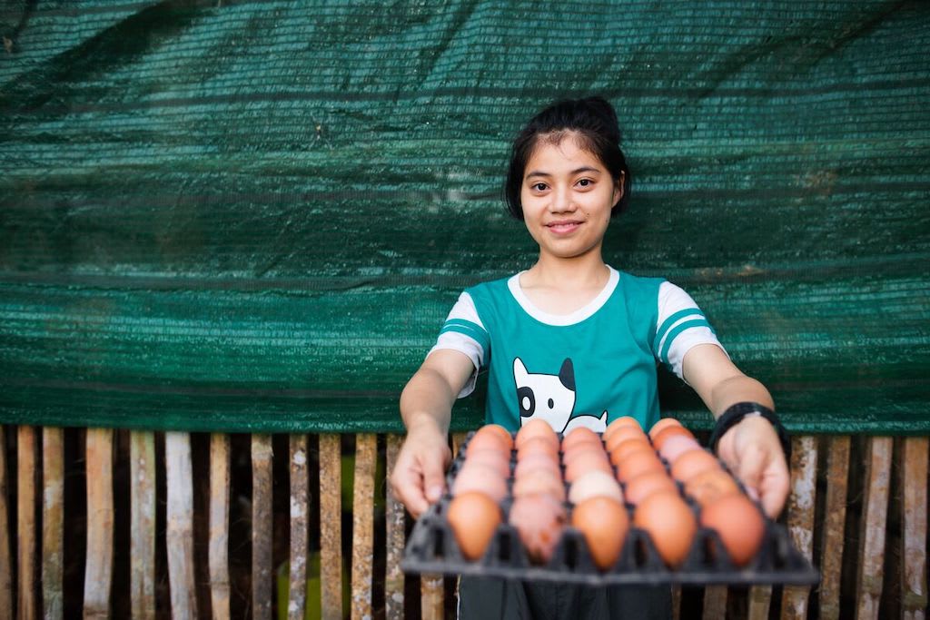 A Thai girl holds a tray of eggs.