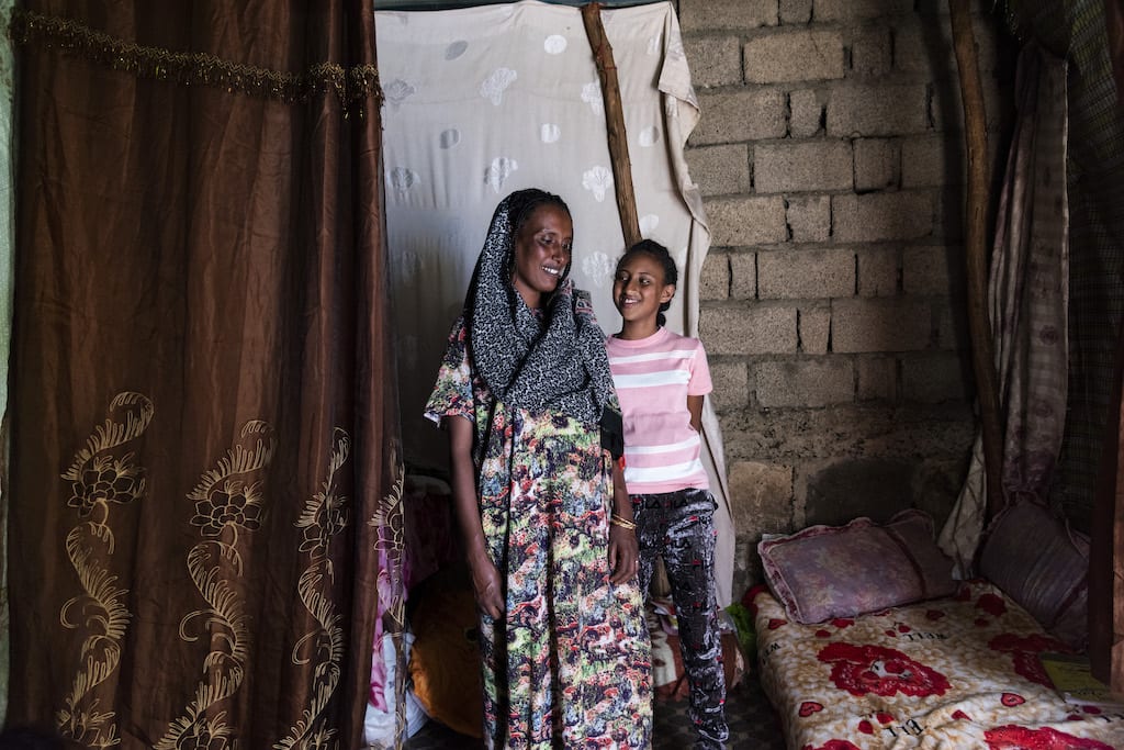 Meseret and Saron stand together in their home.