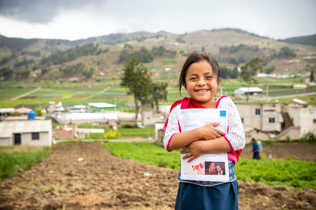 A Ecuadorian girl holds a letter from her sponsor to her chest.