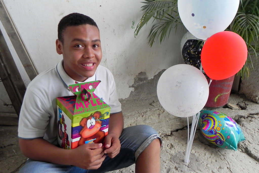 A boy poses with his birthday gift and balloons