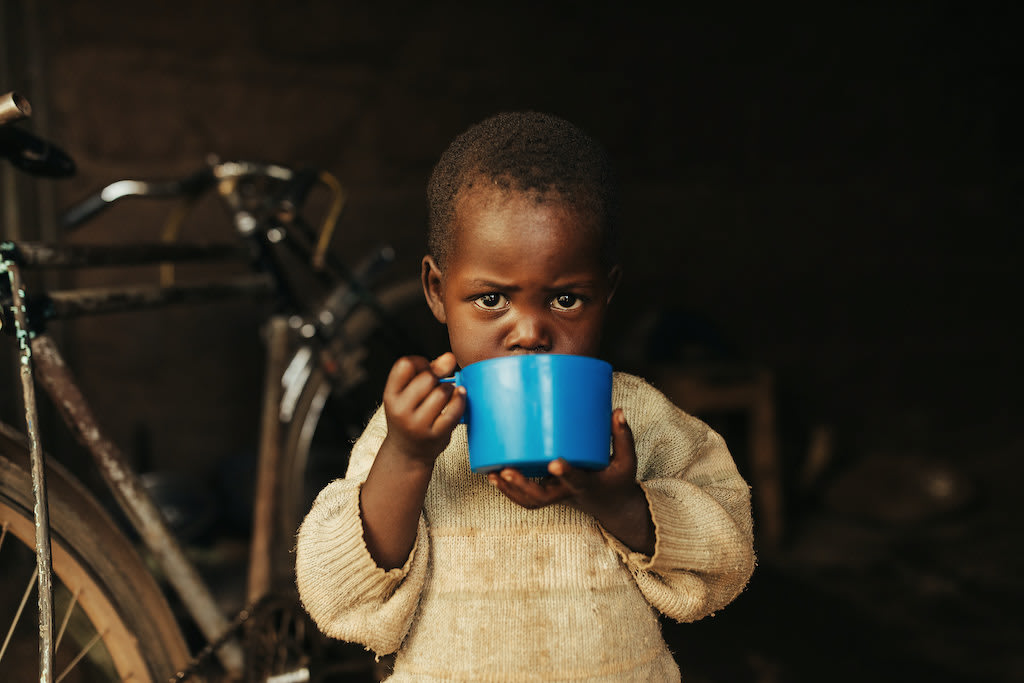 A photo of a Kenyan toddler drinking from a mug.