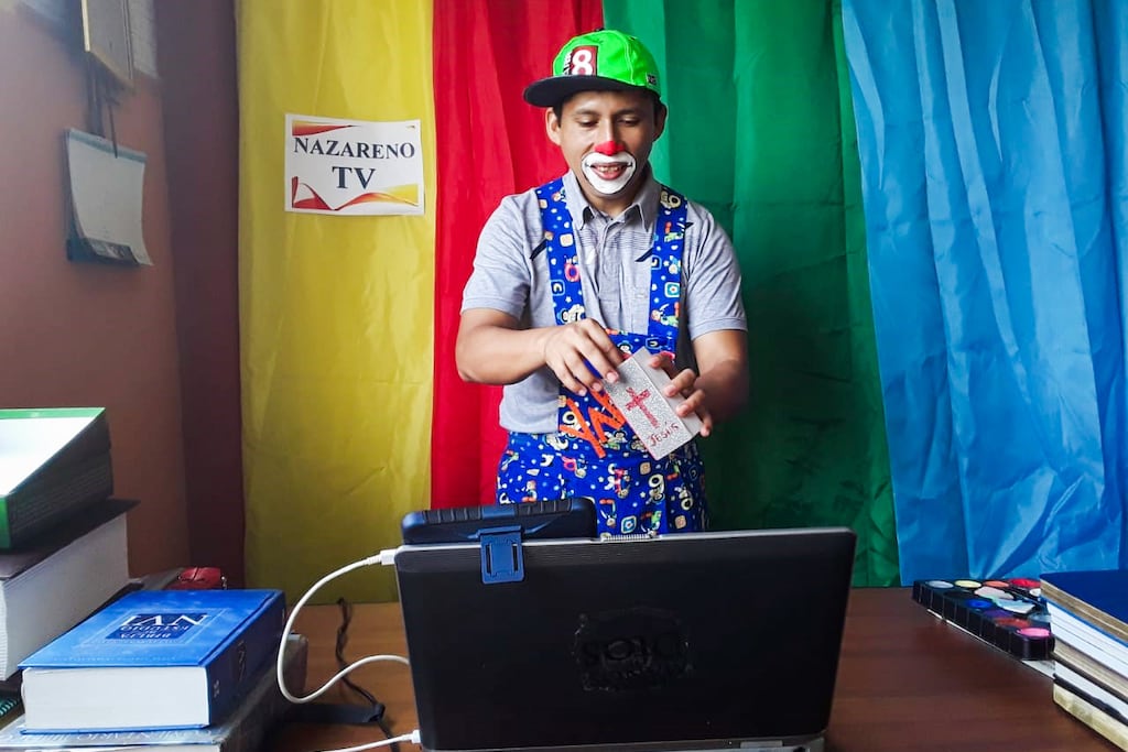 Pastor Alex stands in front of a webcam, dressed as a clown.