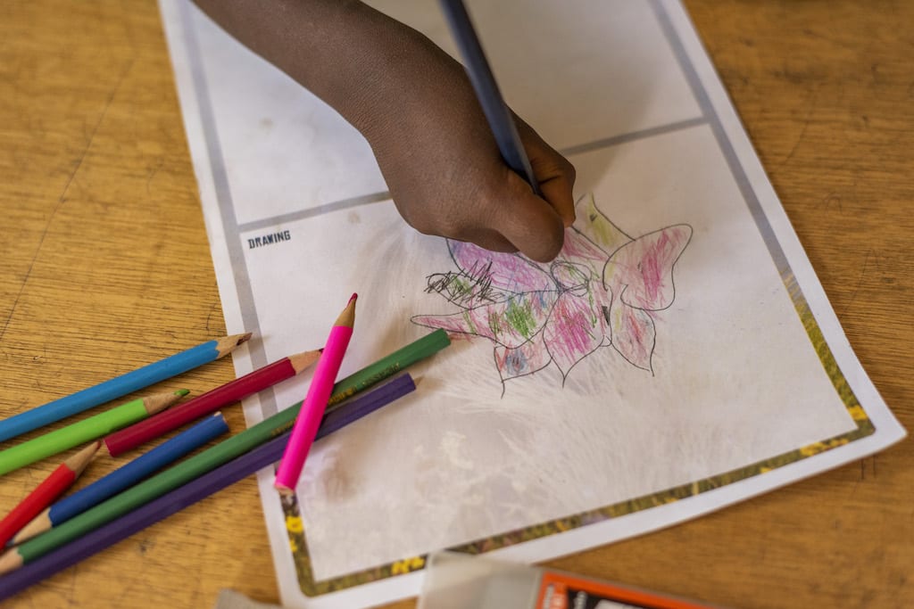 A child's hand drawing a picture.