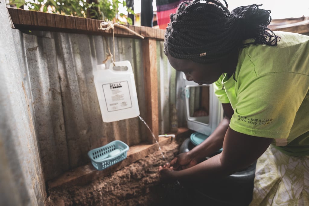 A woman washes her hands using a 'leaky tin'.
