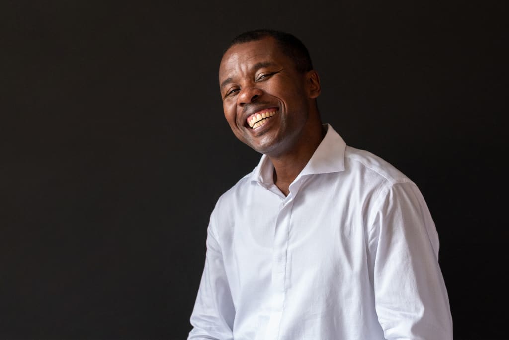 Jean wearing a white button up shirt and smiling broadly.