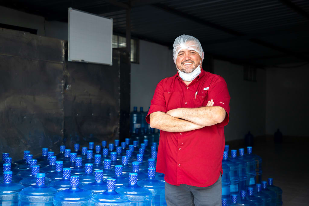 Santiago poses in front of several containers of water.