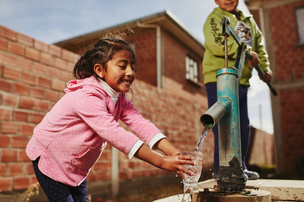 A young girl getting clean water from a borehole pump.