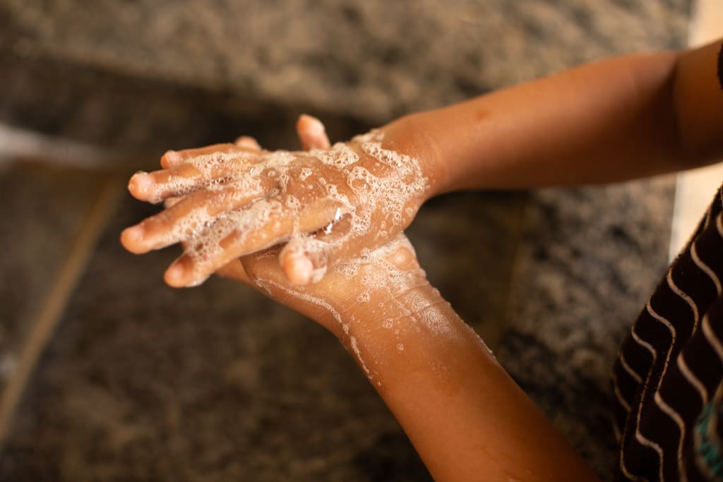 A pair of hands covered in soap suds and being washed.