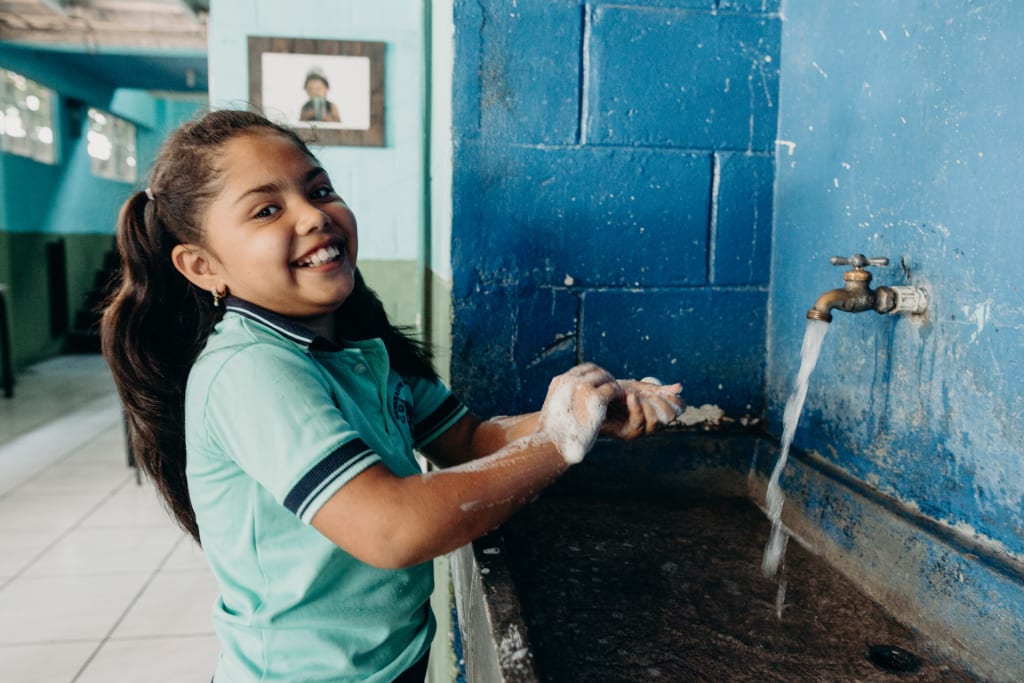 A girl washing her hands at a sink in El Salvador